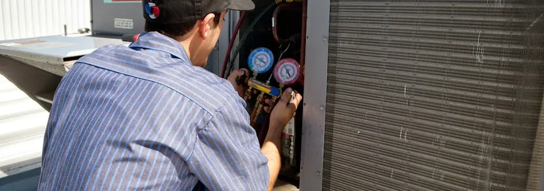 HVAC technician servicing a condenser unit in Titusville